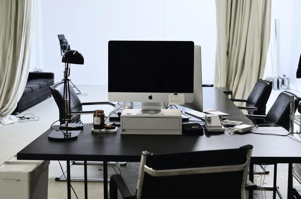 Interior of convenient workspace with contemporary computer placed on table with lamp in modern light office with couch against window