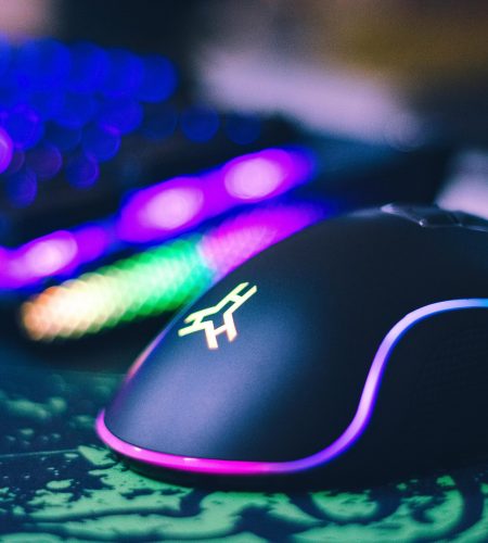 A close-up of a colorful gaming mouse and illuminated RGB keyboard, perfect for tech setups.